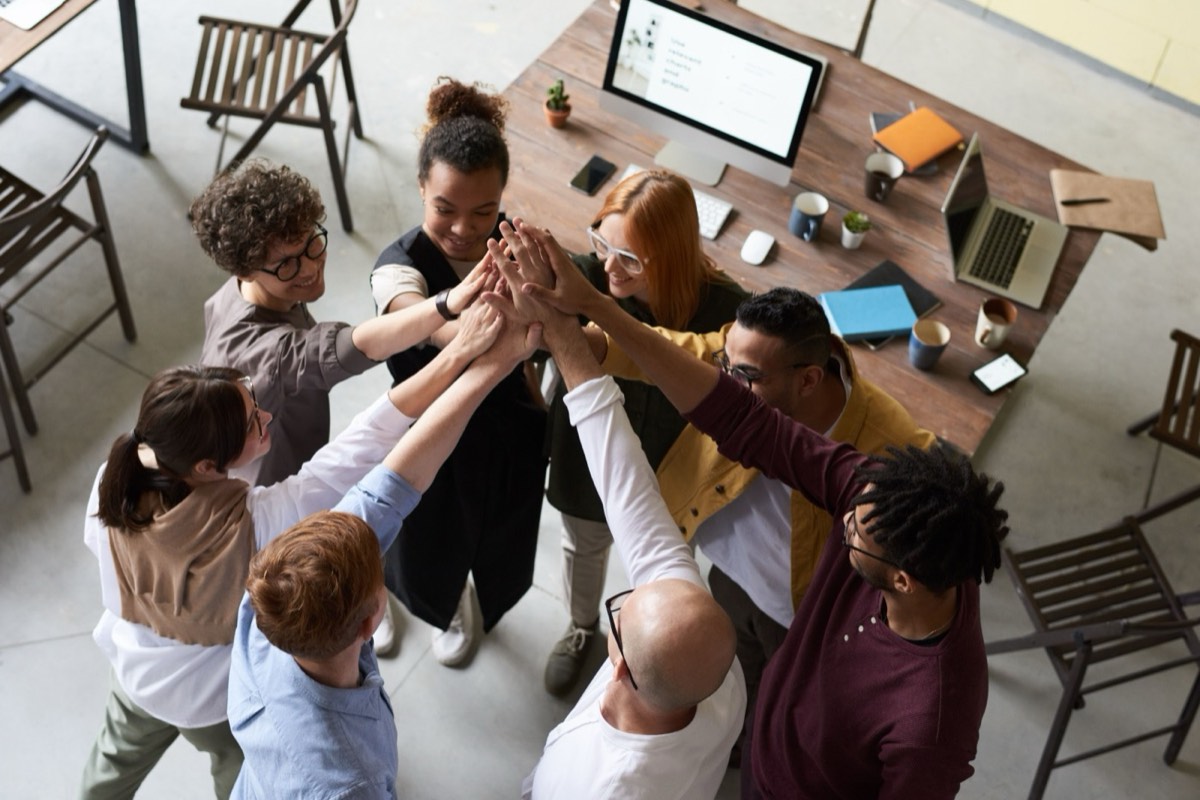 Colleagues stacking hands together, representing organisational culture