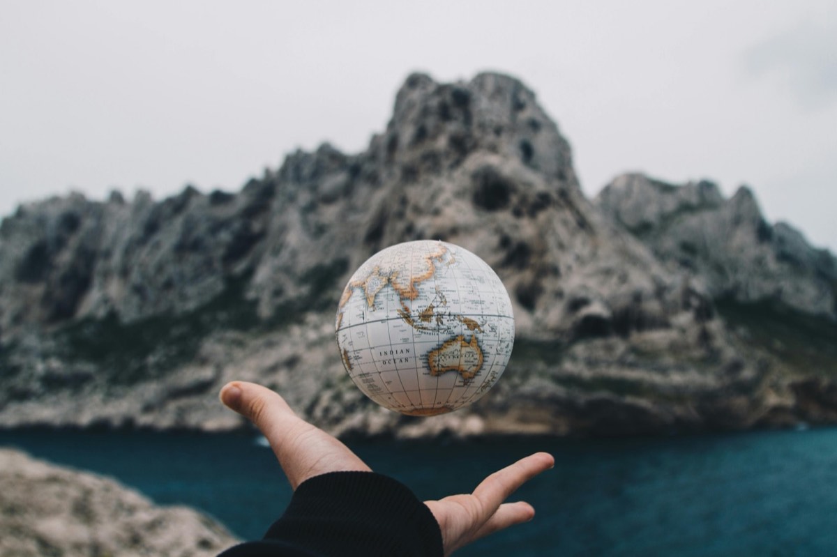 Hand holding a small globe above the sea, representing Eleni's international coaching